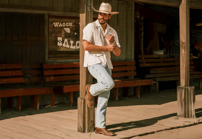 A man standing by a wooden pole wearing the Bowie 11" Western in brown.